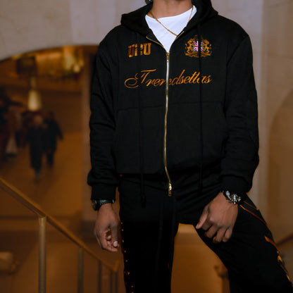 Man wearing a black hoodie with gold text and logos in an indoor setting